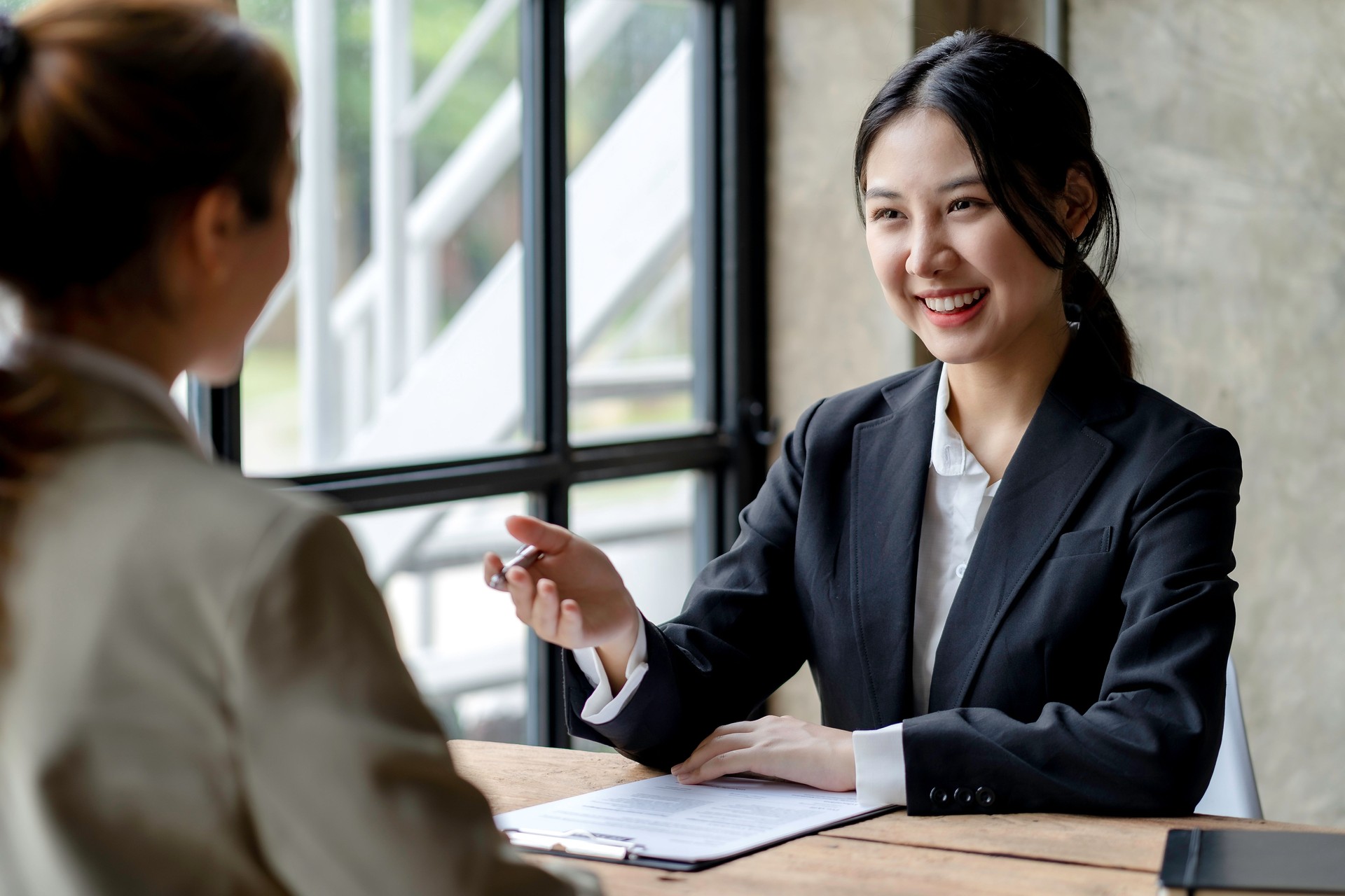 Smiling young Asian businesswomen talking to colleague and exchanging ideas  together at office.