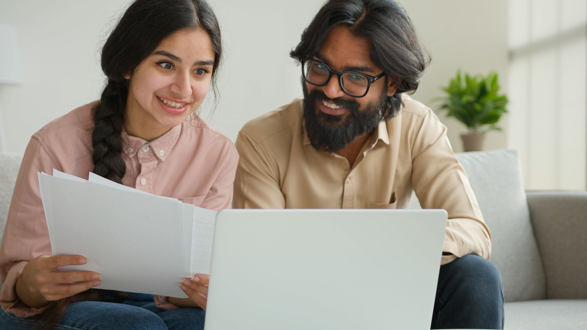 Arabian couple homeowners read tenancy papers at home paying domestic bills taxes online on laptop multiethnic woman and man planning budget talking discuss documents loan payments bank house mortgage